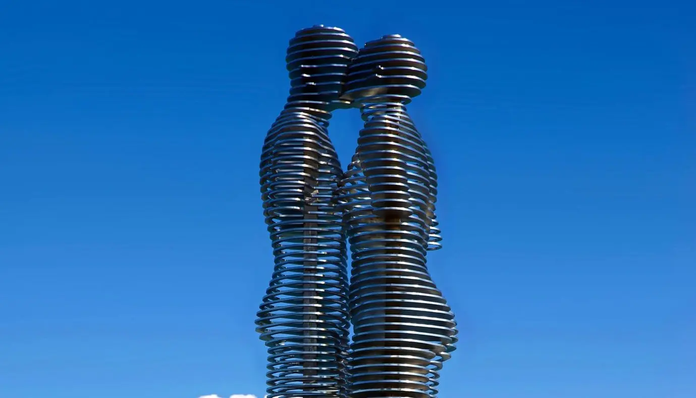The two steel figures of the Ali and Nino sculpture in Batumi, their heads meeting face to face against a blue sky