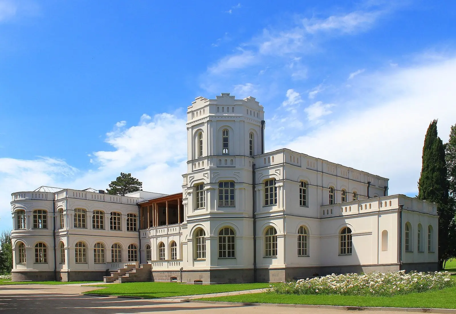 The white Mukhranbatoni palace at Chateau Mukhrani with its tower, lawns and white rose beds under a blue sky