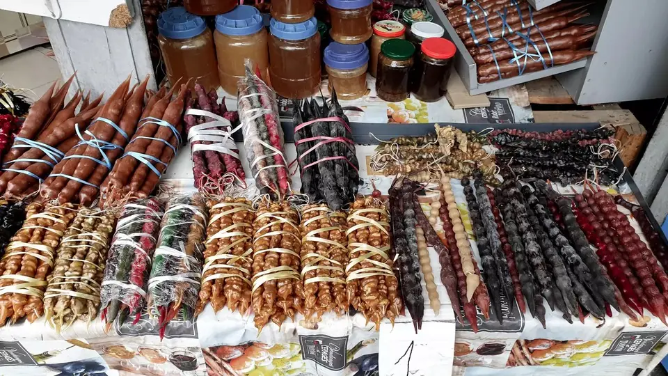 Market stall with rows of churchkhela, dried fruit and jars of honey
