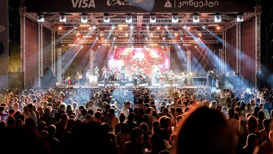 Плотная толпа перед ярко освещенной открытой сценой с группой на Black Sea Jazz Festival