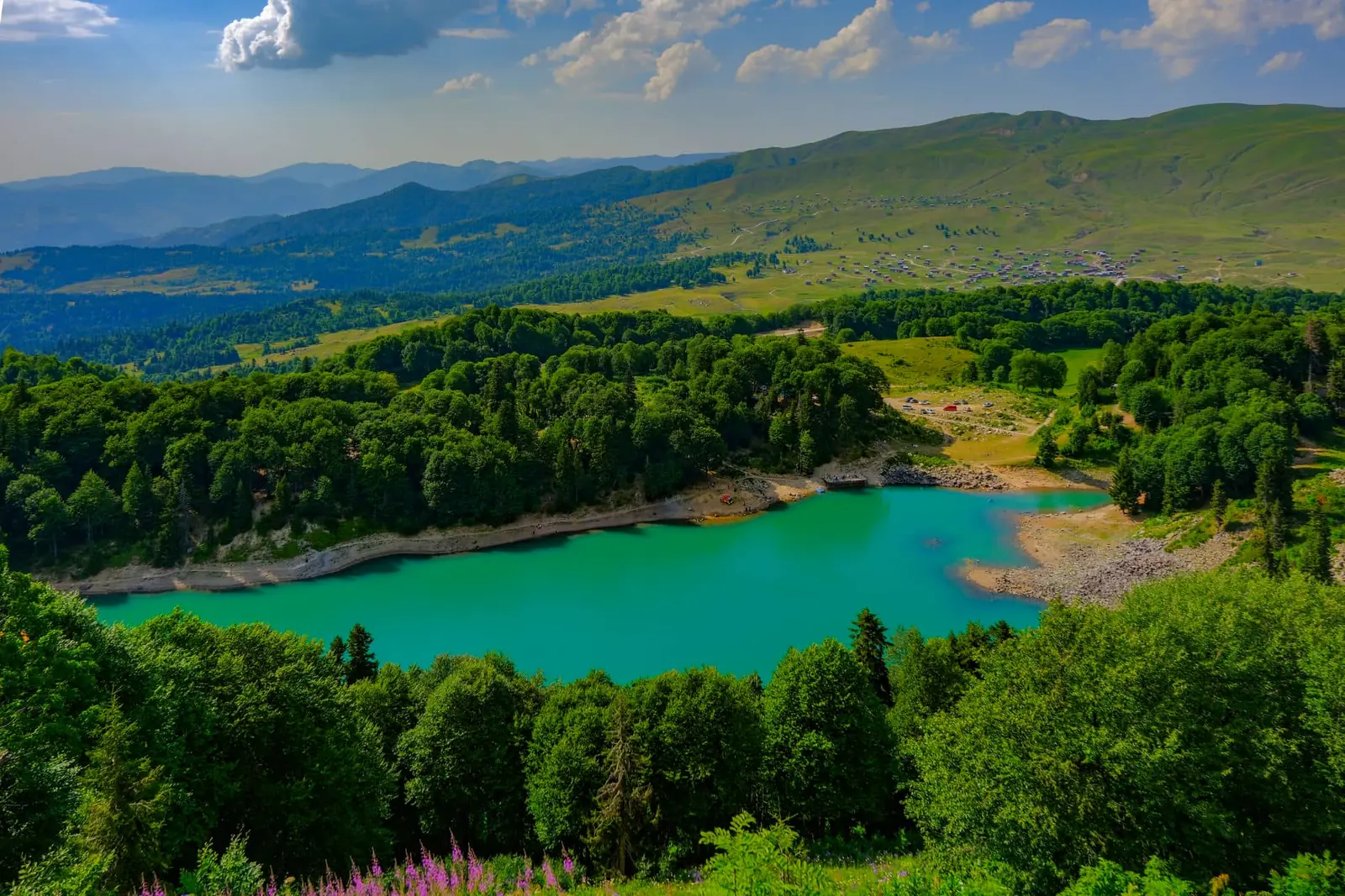 The turquoise Green Lake with summer pastures and hills behind it
