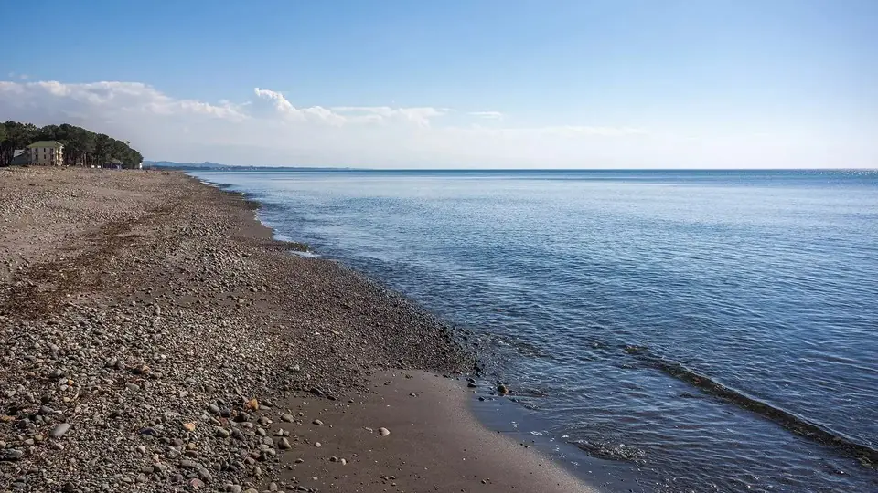 Пустынный пляж с темным песком в Григолети и спокойное Черное море