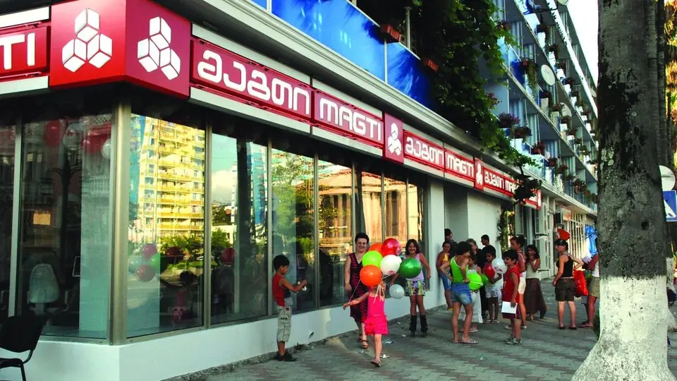 The red shopfront of a Magti mobile phone office on a street in Batumi, with people passing by
