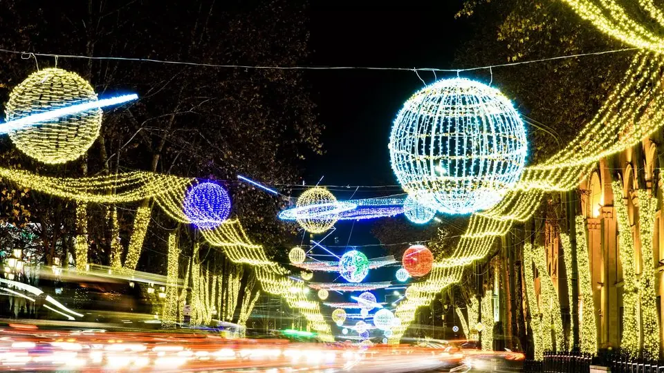 Giant light globes and garlands strung over Rustaveli Avenue in Tbilisi on a December night, with car light trails below