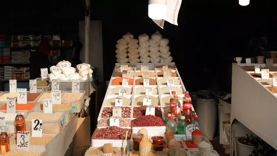 Market stall with spices, beans and grains in boxes marked with handwritten lari prices