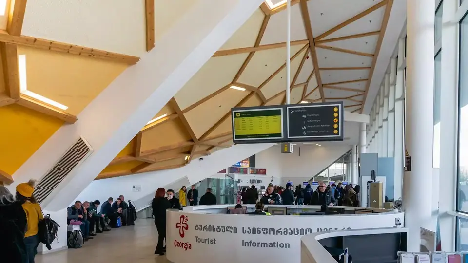 Arrivals hall at Kutaisi airport with travellers at the tourist information desk under a timber roof