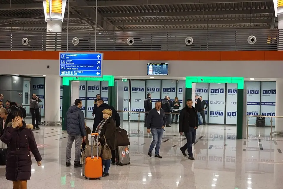 Travellers with suitcases walking out of the arrivals hall at Tbilisi airport