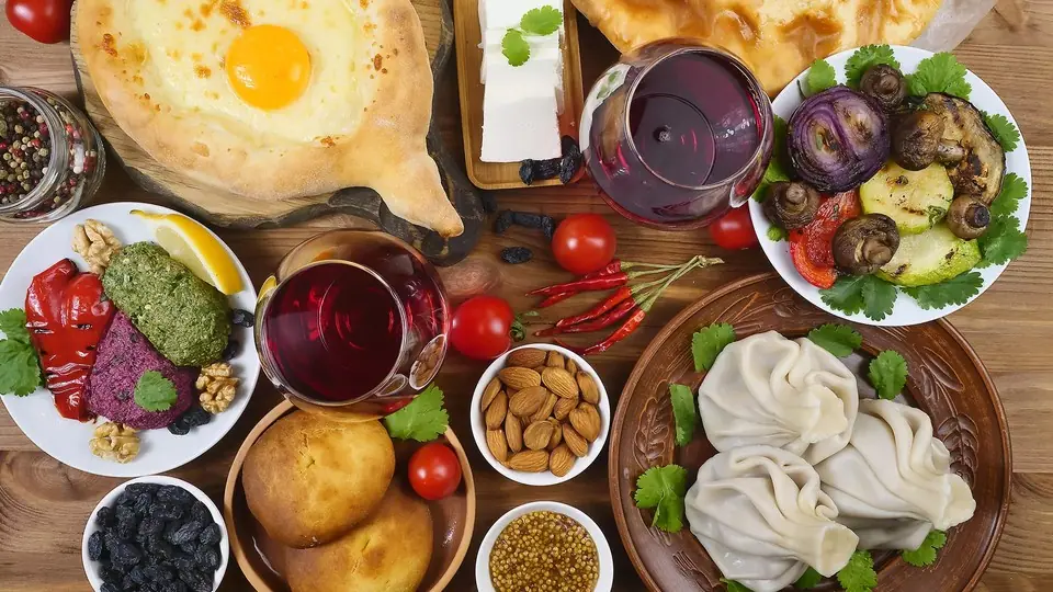Table seen from above with khinkali, khachapuri, pkhali, red wine and fruit