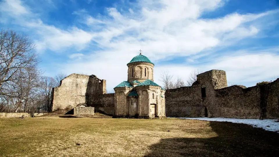 Небольшая купольная церковь Кветера с зелеными крышами внутри разрушенных каменных стен крепости