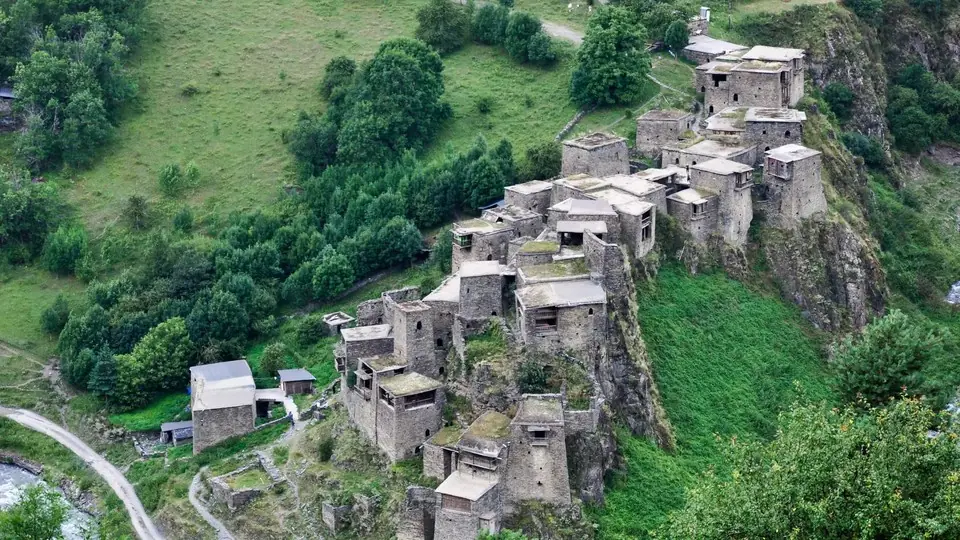 Clustered stone towers of Shatili on a steep green slope above the river