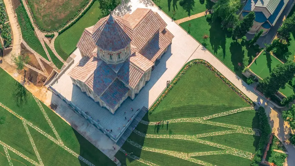 Aerial view of Bodbe Monastery church with tiled roofs among patterned green lawns