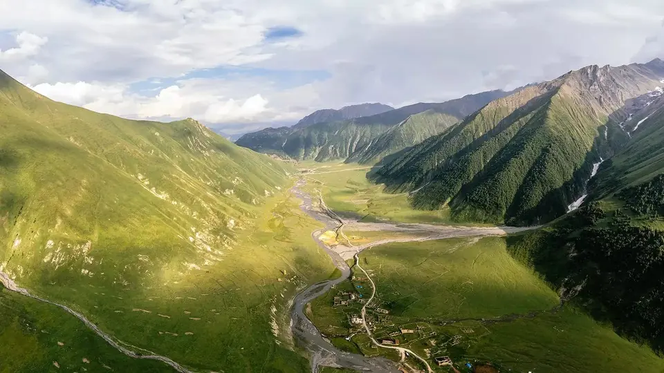 Aerial view of the green Truso valley with the braided Tergi river below steep slopes