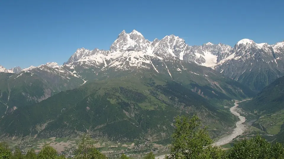 The twin snowy summits of Ushba above the green Mestia valley, seen from the Zuruldi ridge